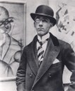 Ritratto fotografico di Gino Severini accanto a Autoritratto del 1913.jpg